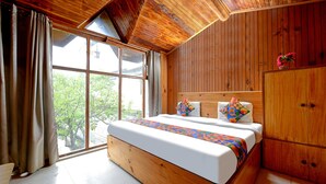 A wooden bedroom with a large bed, a wardrobe, and a window with curtains. - Fabhotel Attithi Huts And Cottage (Manali)