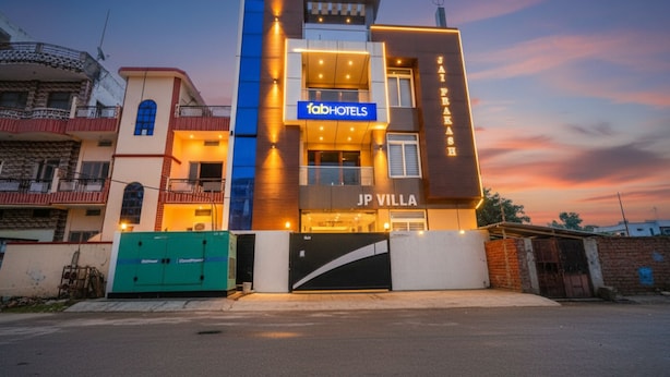 En moderne bygning med 'fabHOTELS' skiltning, 'JP VILLA' branding og et tydeligt 'JAI PKASH' skilt.