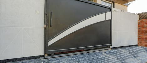 A closed metal gate with a curved design, a concrete wall, and a brick wall to the right.