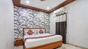 Un dormitorio con cama, mesita de noche y pared decorada con un diseño de hojas.