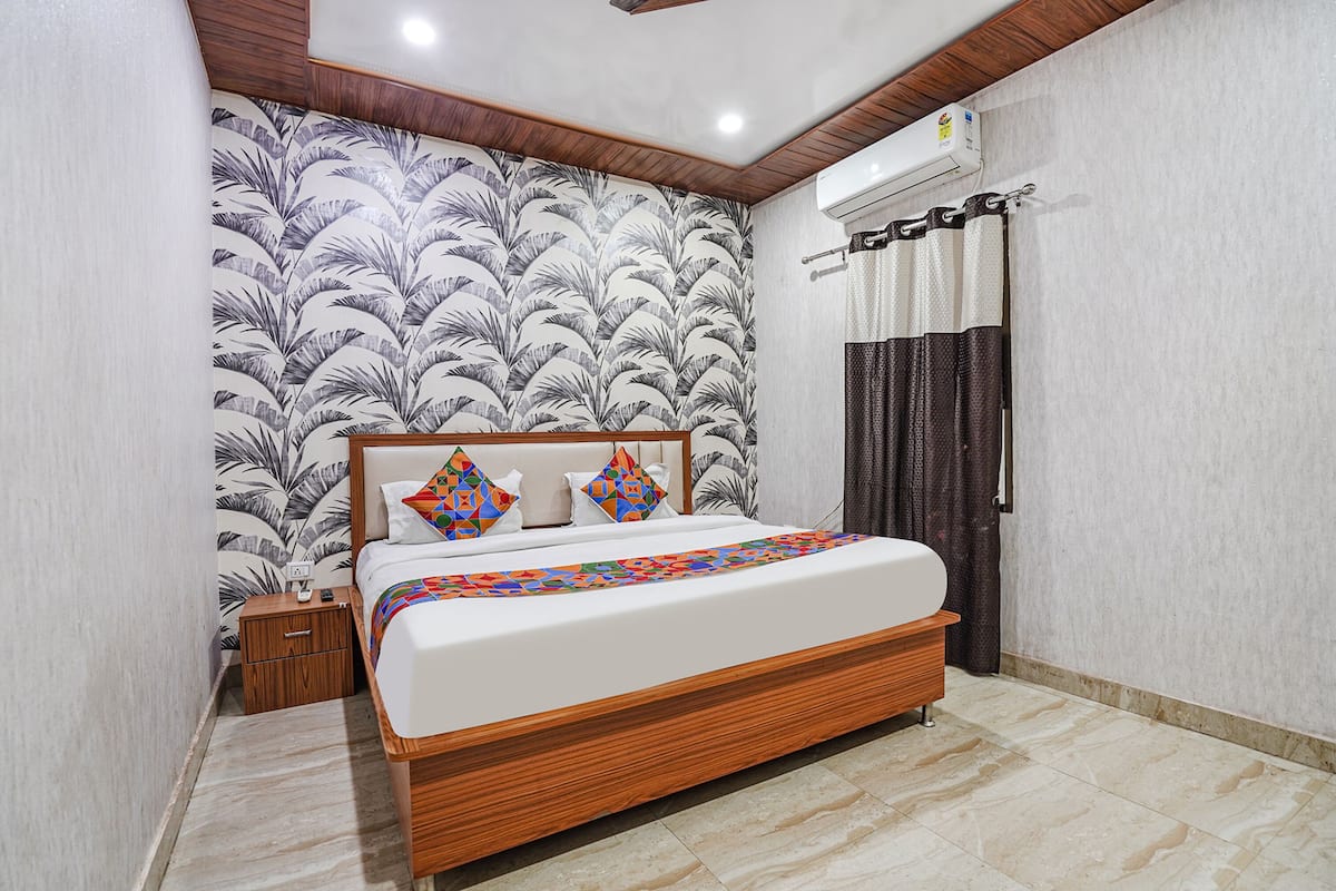 Un dormitorio con cama, mesita de noche y pared decorada con un diseño de hojas.