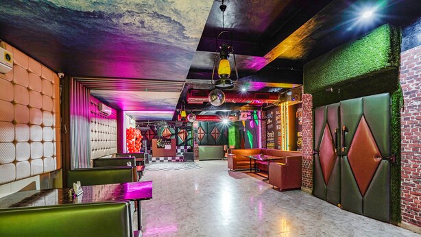 Un interior moderno con suelo a cuadros, asientos verdes y rojos, y una bola de discoteca.