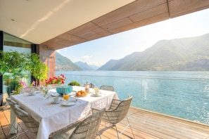 A table set for breakfast with a view of a lake and mountains.