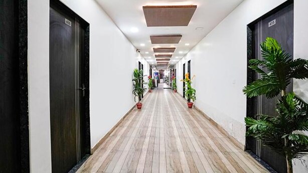 A hallway with wooden flooring, black doors, and potted plants. - Fabhotel Royal City (Ahmedabad)