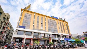 A multi-story building with a yellow facade, a visible entrance, and a sign for a hotel. - Fabhotel Royal City (Ahmedabad)