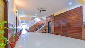 Un couloir d’hôtel avec un escalier, des plantes en pot et un ventilateur de plafond.