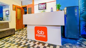 A reception area with a checkered floor, a sofa, a refrigerator, and a wall-mounted screen. - Fabexpress Regal (Indore)