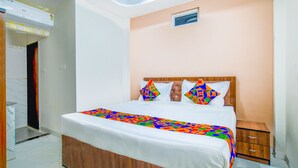 A bedroom with a bed, a nightstand, and a wall-mounted air conditioner. - Fabexpress Regal (Indore)