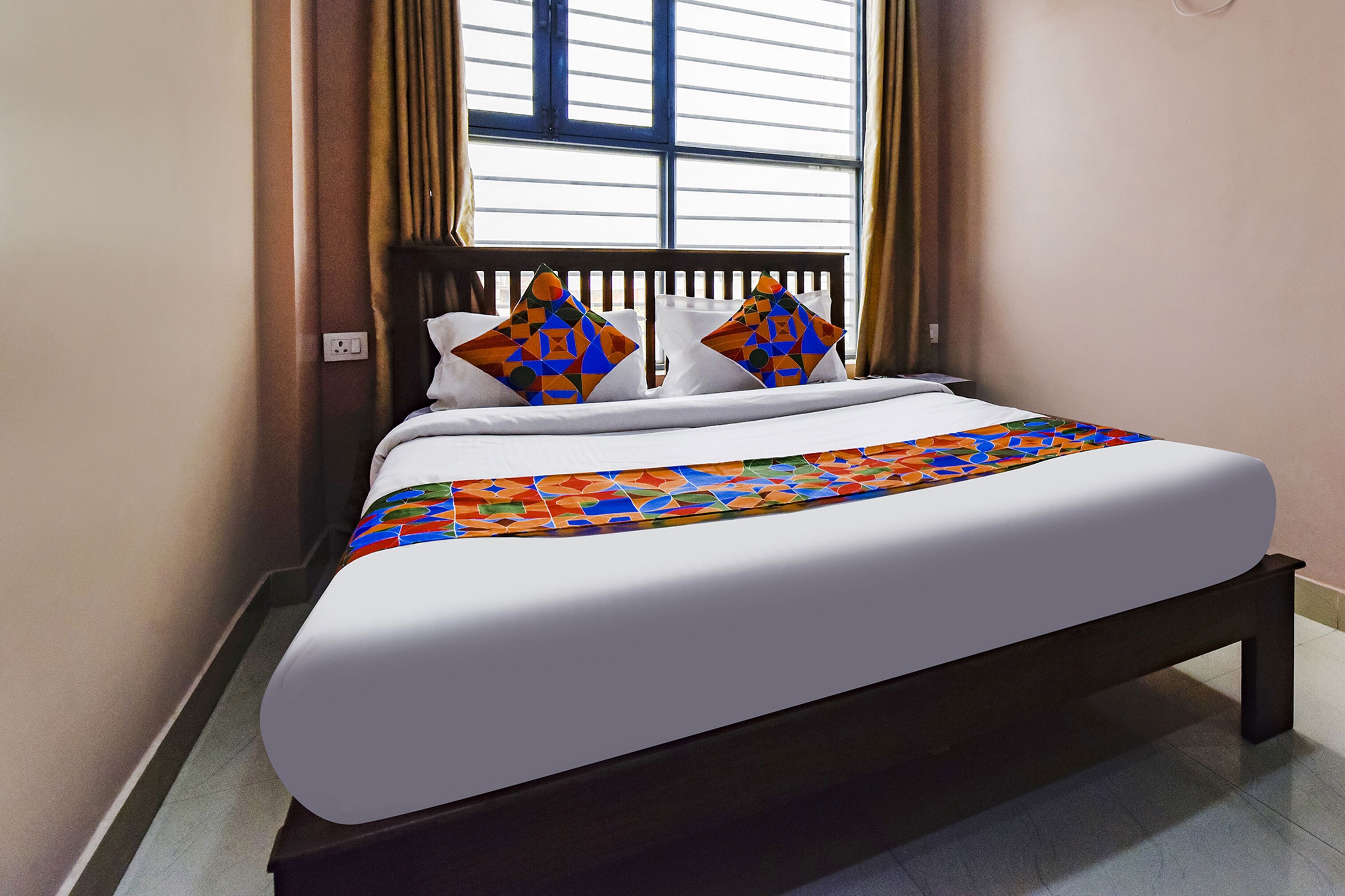 A neatly made bed with a colorful geometric-patterned bedspread and two decorative pillows.