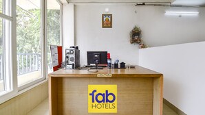 Un mostrador de recepción con detalles de madera, un letrero que dice "fab hotels" y una ventana con vistas a la vegetación.