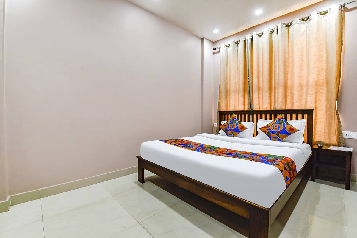 A neatly made bed with a colorful blanket, a wooden headboard, and a nightstand with a lamp.