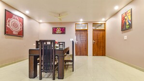 Un pasillo espacioso con un comedor que incluye una mesa y sillas de madera, dos puertas de madera y ventiladores de techo.