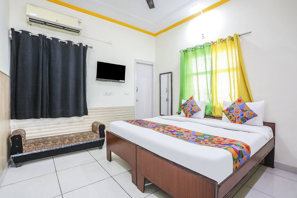 Una habitación de hotel con cama, sofá, televisor y aire acondicionado.