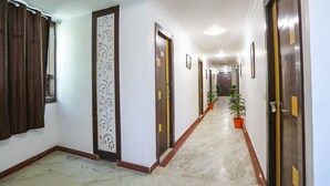 A hallway with doors, a decorative panel, and potted plants. - Fabhotel Br International (Agra)