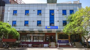 A hotel with a modern facade, multiple air conditioning units, and a visible entrance with steps. - Fabhotel Br International (Agra)