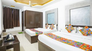 A hotel room with two beds, a wardrobe, a desk with a kettle, and a ceiling fan. - Fabhotel Br International (Agra)