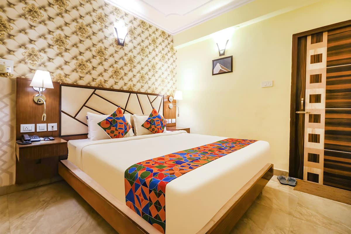 A neatly made bed with a colorful geometric bedspread, a headboard with a geometric design, and two bedside lamps.