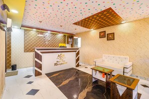 A hotel reception area with a marble floor, a reception desk, a white sofa, and a patterned ceiling. - Fabhotel Magadh Palace (Danapur)