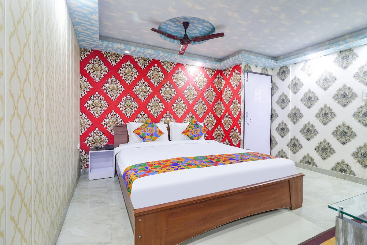 A bedroom with a bed, a ceiling fan, and patterned wallpaper.