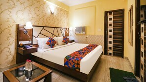 A hotel room with a bed, bedside tables, a nightstand, a lamp, a wall-mounted air conditioner, and a door with a striped pattern. - Fabhotel Magadh Palace (Danapur)