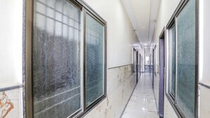 Un passadís llarg i estret amb grans finestres a banda i banda, que condueix a una porta al final.