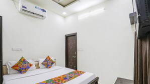 Habitació d'hotel amb llit, televisió, aire condicionat i una porta.
