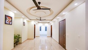 A spacious hallway with a ceiling fan, recessed lighting, and a potted plant. - Fabhotel Indian (Gurugram)