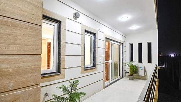 A modern building with a flat roof, large windows, and a balcony with a railing. - Fabhotel Indian (Gurugram)