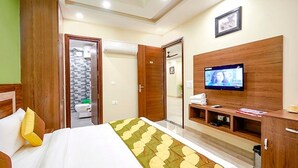 A hotel room with a bed, a television, a bathroom, and a wooden wardrobe. - Fabhotel Indian (Gurugram)