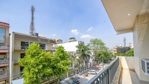 Un balcon donnant sur une rue, des immeubles et un ciel dégagé.