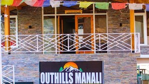 A building with a stone facade, a balcony with a white railing, and a sign that reads "Outhills Manali". - Fabhotel Outhills (Manali)