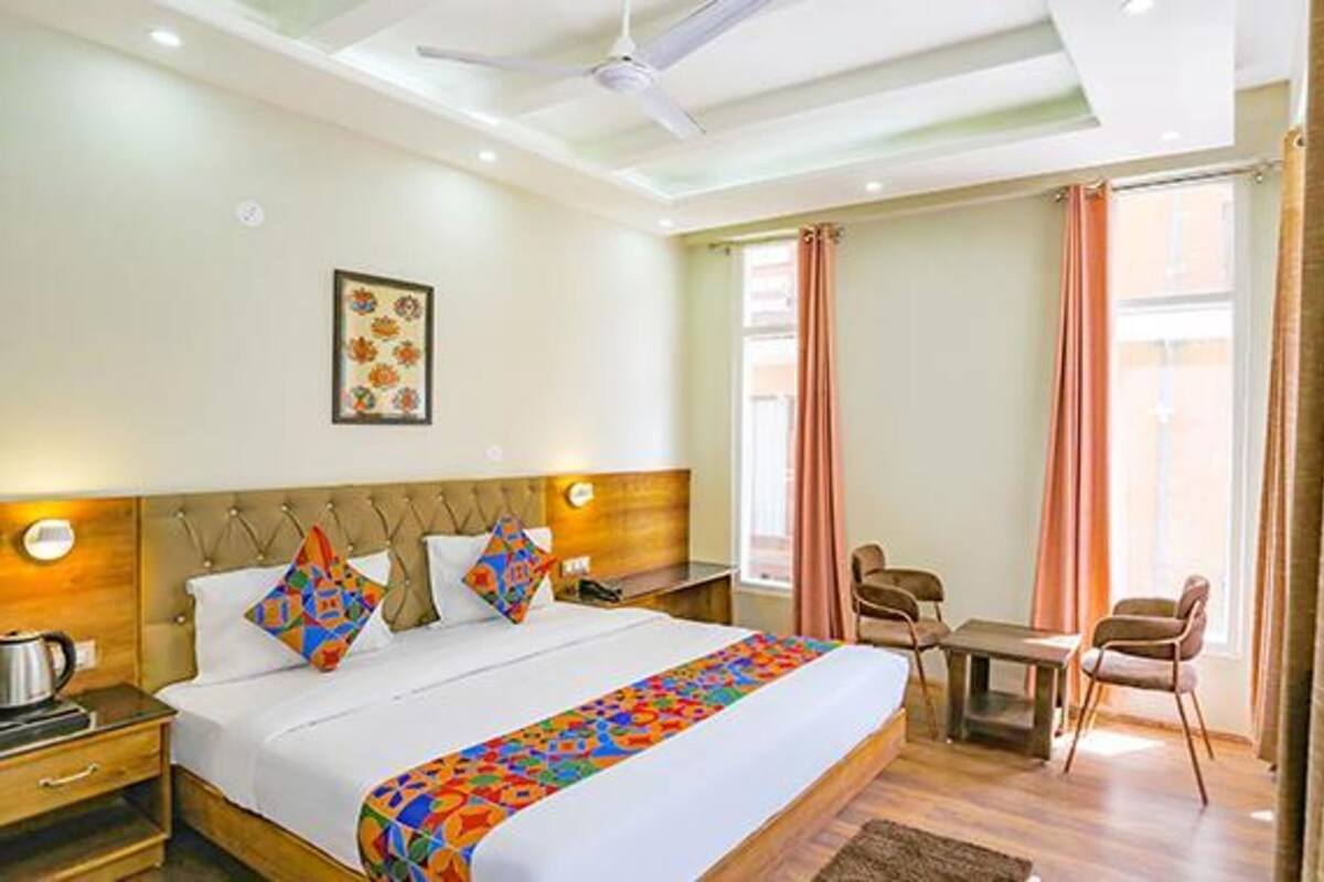 A hotel room with a bed, a desk, a chair, and a window with curtains.
