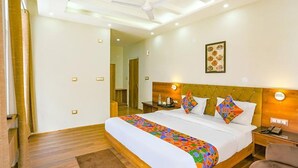 A hotel room with a large bed, a wooden headboard, a bedside table with a lamp, and a framed picture on the wall. - Fabhotel Outhills (Manali)