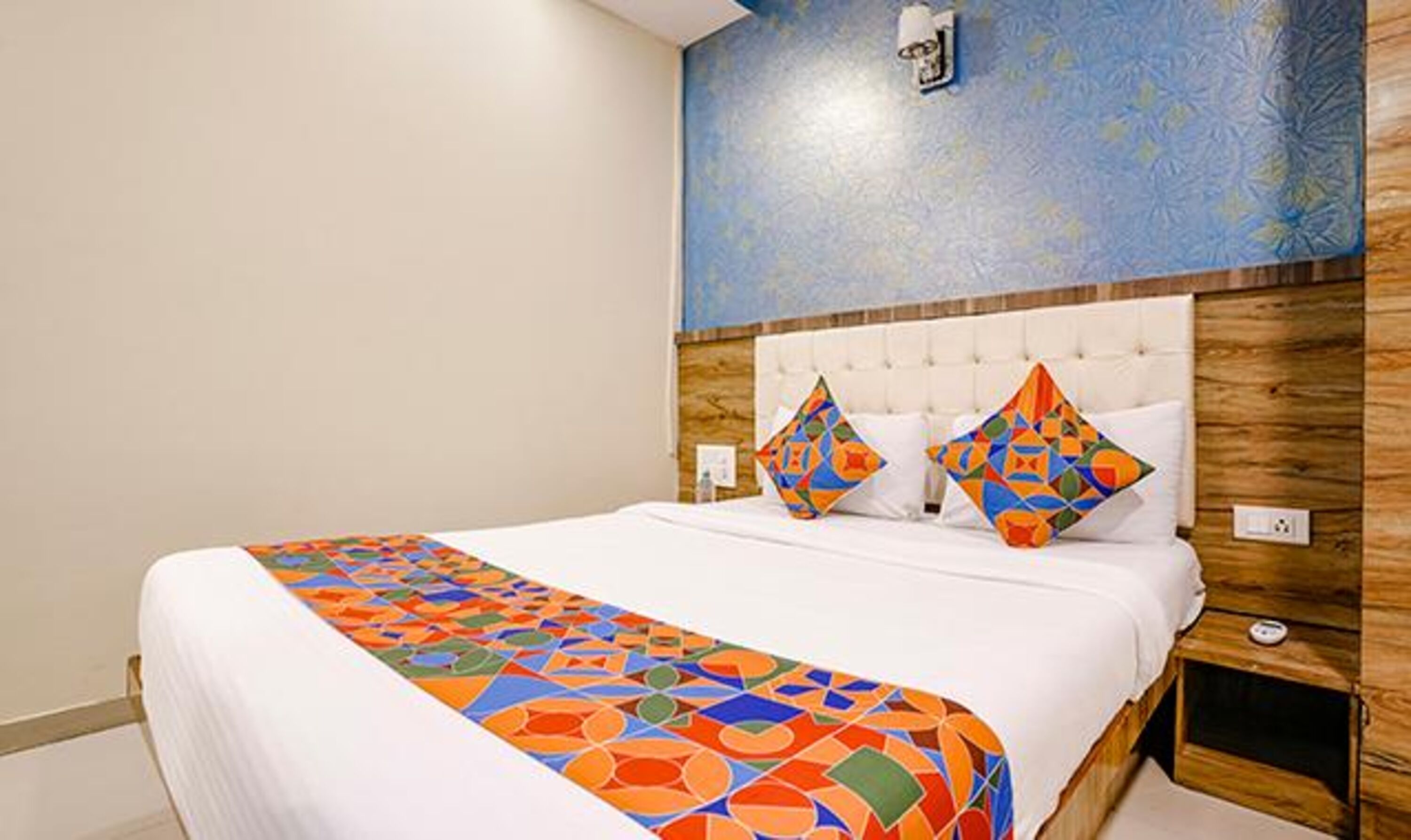 A hotel room with a large bed, a wooden headboard, and a blue textured wall.
