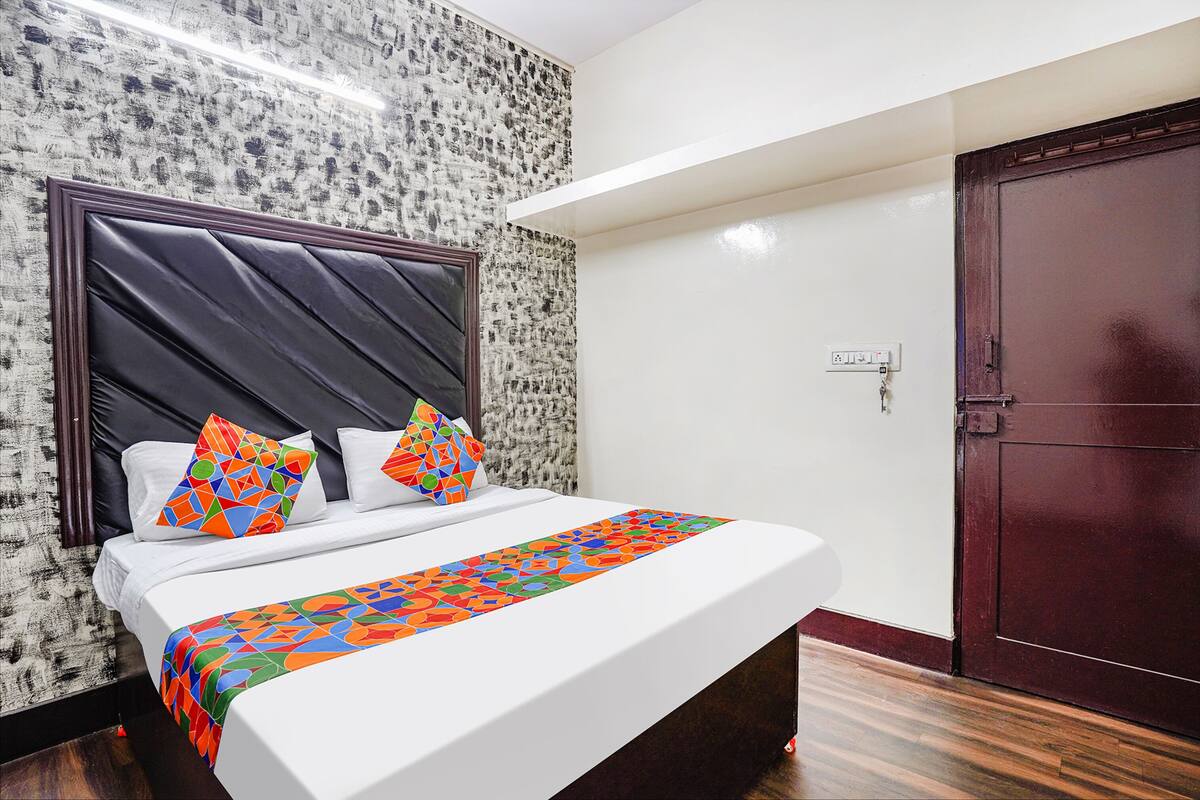 Habitación de hotel con una cama, una puerta de madera oscura y una pared con textura.