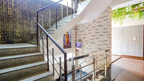 A staircase with metal railings, a wall with a leaf pattern, and a water dispenser. - FabHotel Pavithraa Edition (Bengaluru)