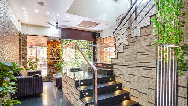 A modern interior with a staircase, seating area, and decorative plants. - FabHotel Pavithraa Edition (Bengaluru)