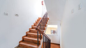 A wooden staircase with a black handrail leading to a landing. - FabExpress California Inn (Kodaikanal)