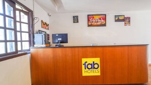 A reception desk with a 'fab hotels' logo, a computer, and artwork on the wall. - FabExpress California Inn (Kodaikanal)
