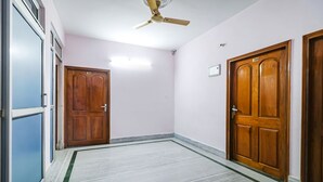 Un passadís amb dues portes de fusta, un ventilador de sostre i un paviment de marbre.