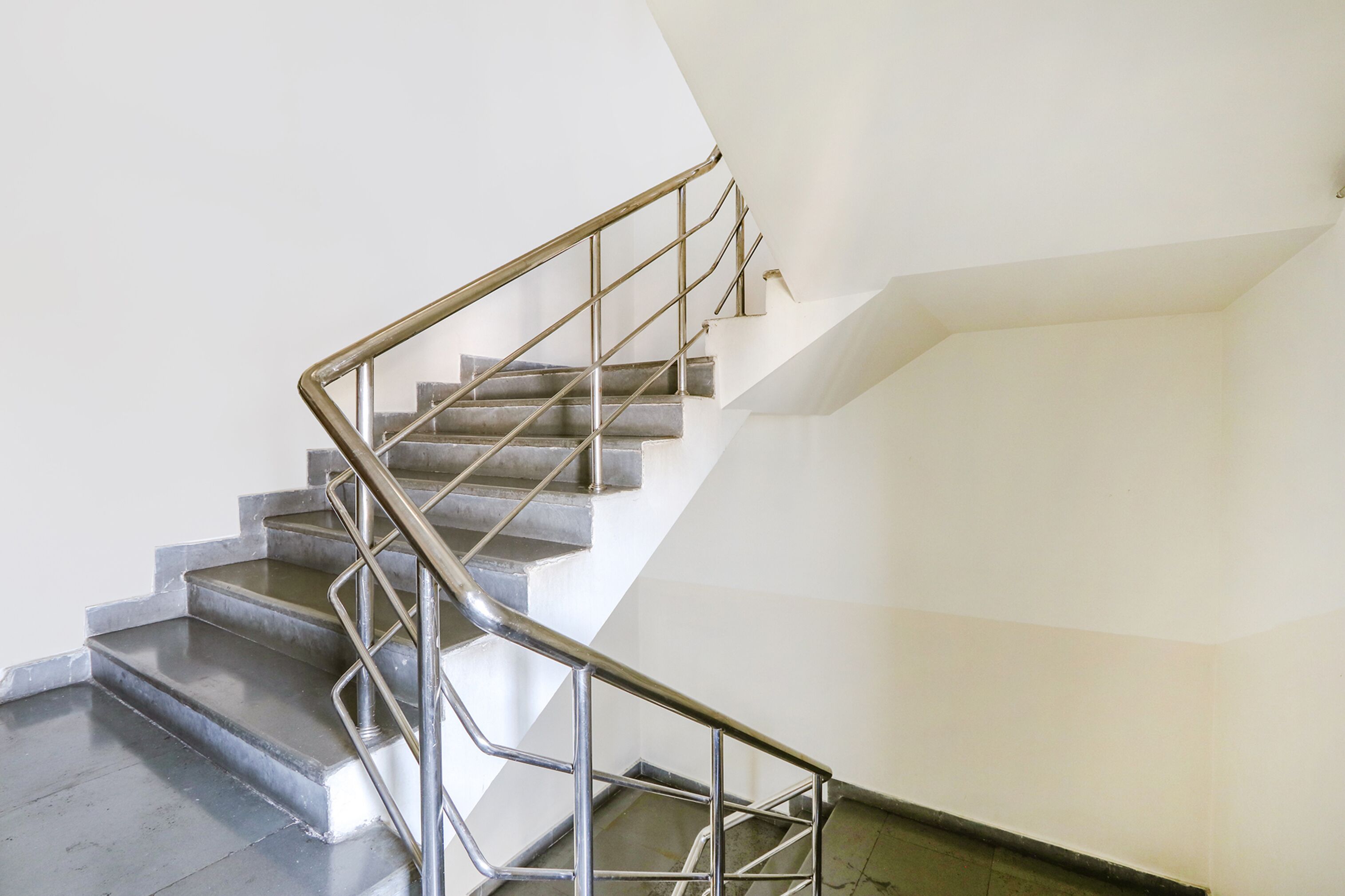 A staircase with metal railings and a plain white wall.