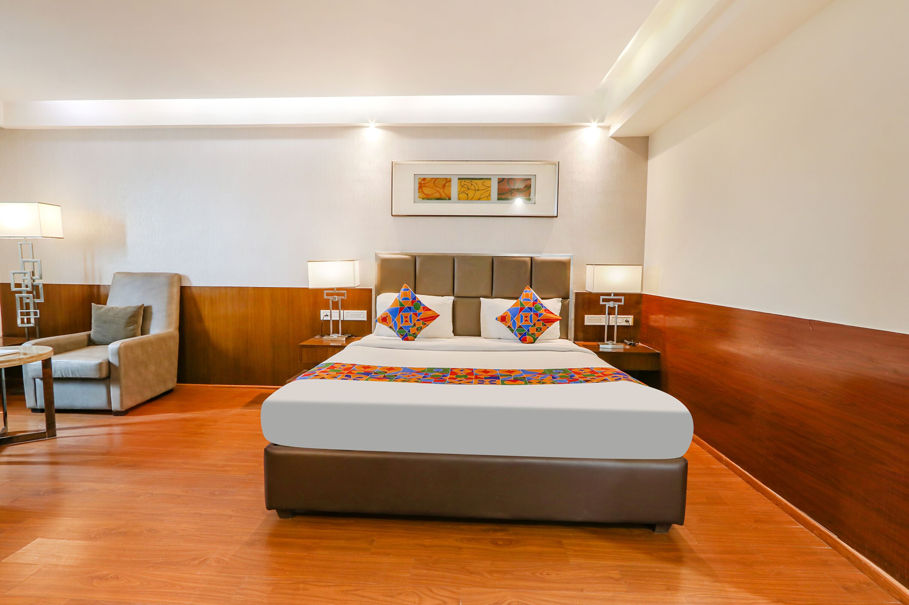 A hotel room with a large bed, a chair, a nightstand, and a lamp.