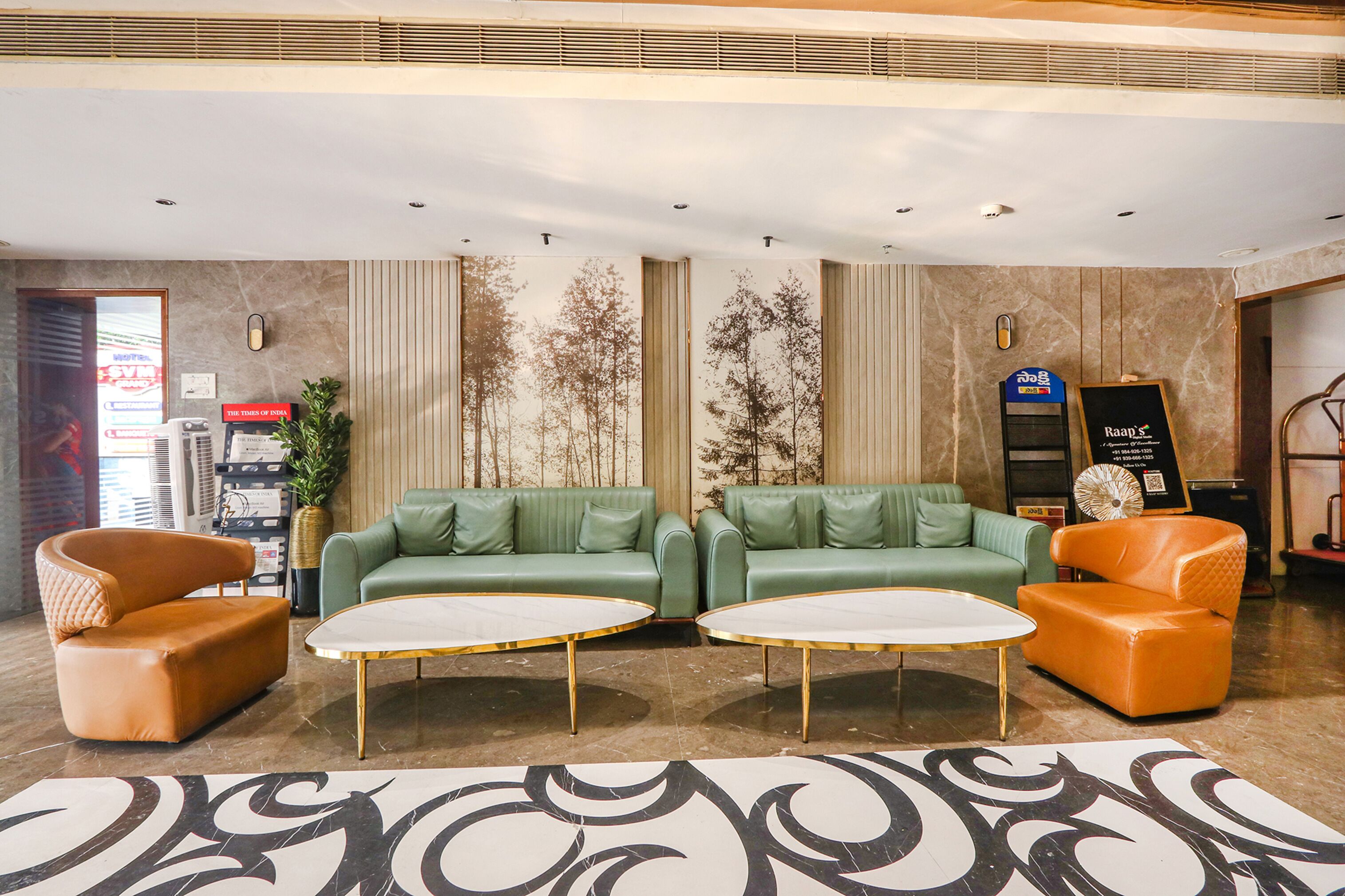 A lobby with two green sofas, an orange armchair, and a white coffee table.