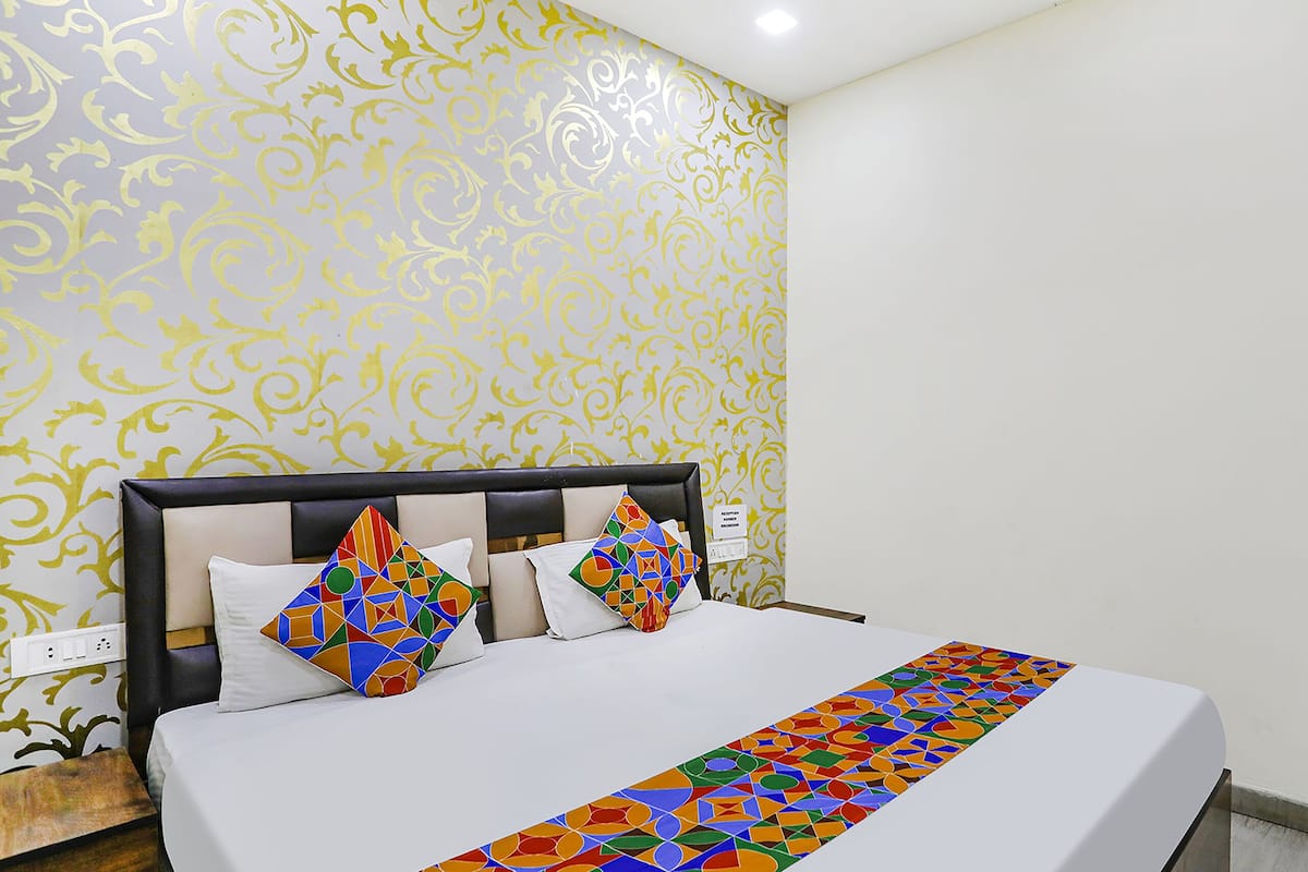 A hotel room with a bed, a headboard, and a patterned wallpaper.