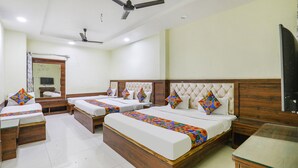 A hotel room with three beds, a ceiling fan, a large mirror, and a TV. - Fabhotel Naresh Palace (Raipur)