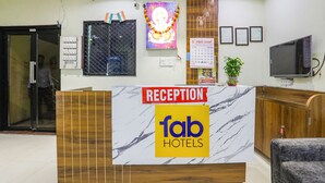 A reception desk with a marble top, a reception sign, a calendar, framed certificates, and a television. - Fabhotel Naresh Palace (Raipur)