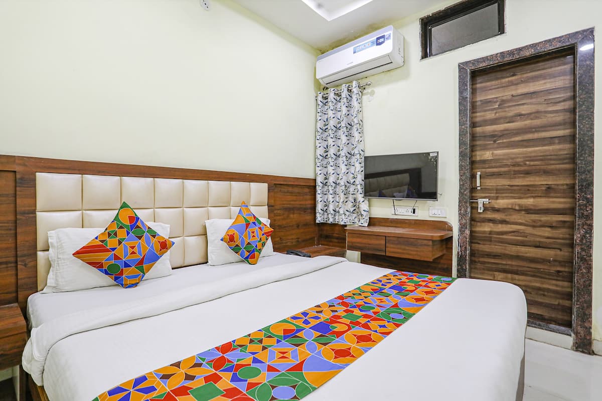 Ein Hotelzimmer mit Bett, Fernseher, Klimaanlage und Holztür.