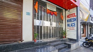 A hotel entrance with a sign reading "Hotel Naresh Palace," a closed shutter door, and a motorcycle parked outside. - Fabhotel Naresh Palace (Raipur)