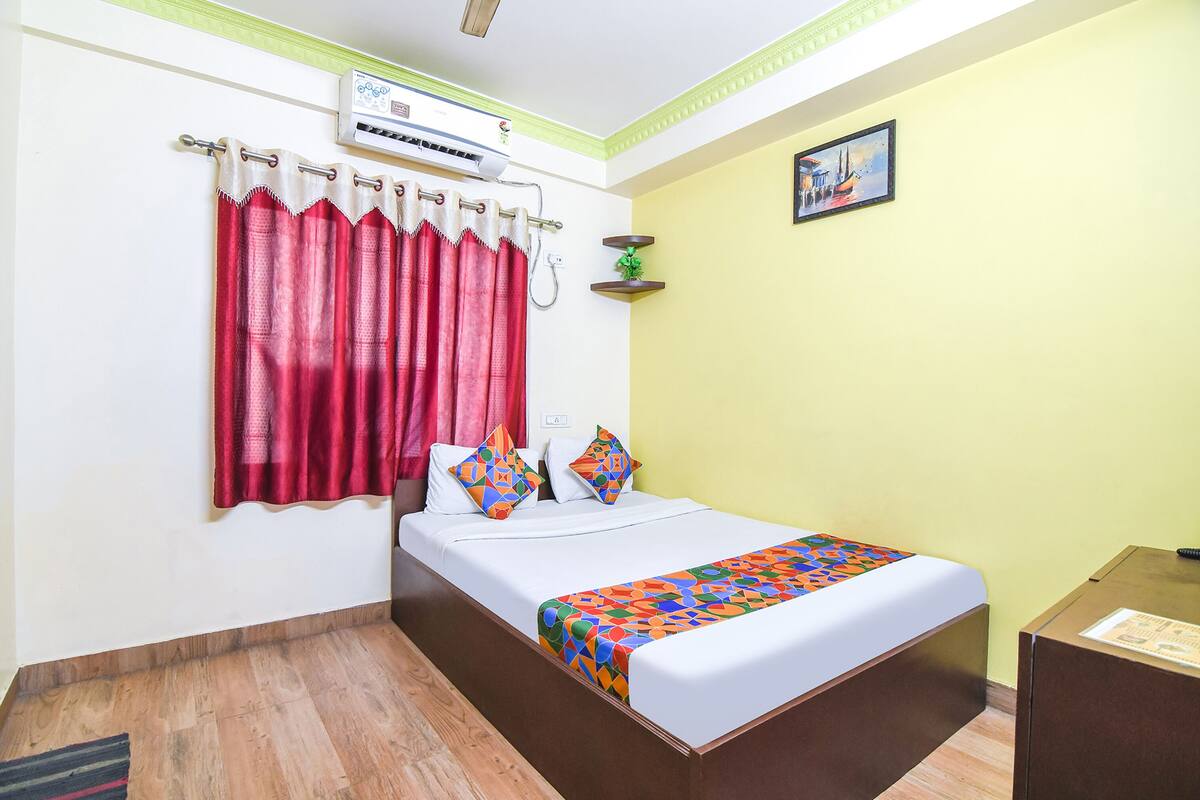 A neatly arranged hotel room with a bed, a desk, and a window with curtains.