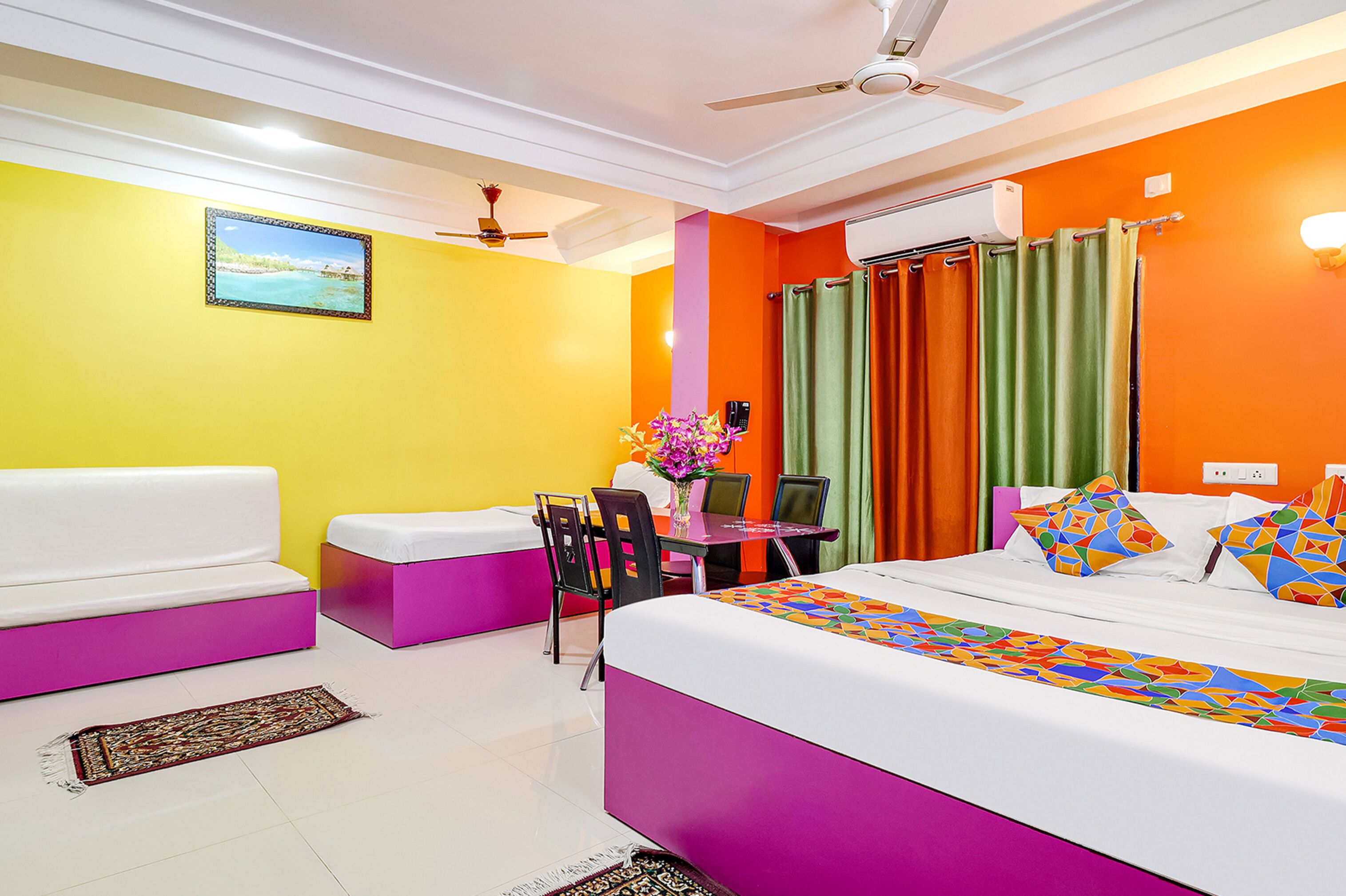 A brightly colored hotel room with a bed, a desk, a chair, and a sofa.